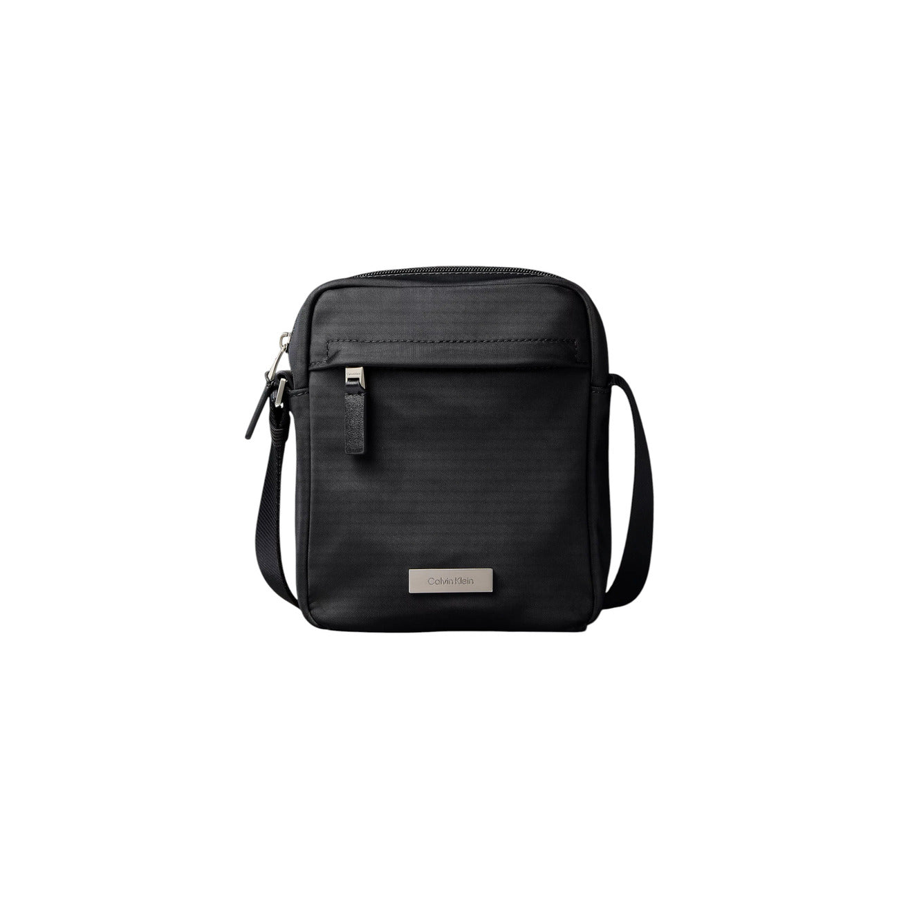Borsa Tracolla Uomo Calvin Klein Clean Reporter; Nero. 100% Nylon riciclato ecosostenibile, doppia chiusura con zip, tracolla regolabile in tessuto e divisori interni. Dimensioni compatte (16x20 cm), stile minimalista e leggero. Vista frontale 