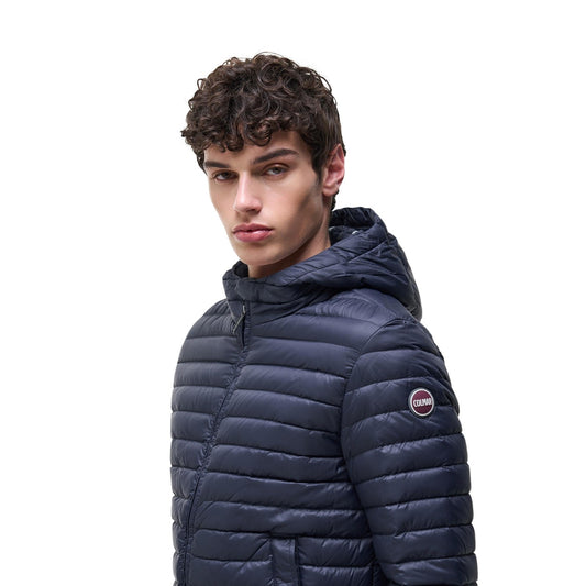 Piumino uomo Colmar Originals blu navy 100 grammi 1245 8VX. Giacca leggera da uomo blu scuro in tessuto opaco idrorepellente con interno a contrasto, cappuccio fisso, bottone al collo, zip doppio cursore e bordo elastico logato, giubbotto primaverile casual sportivo.