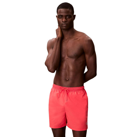 Boxer mare Calvin Klein CK Monogram; 100% poliestere impermeabile, vita elastica con coulisse, tasche multiuso, slip interno in rete. Stile iconico ispirato agli archivi. Colore corallo 