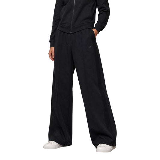 Pantaloni Tuta Neri Donna Guess Active Lyra; Taglio dritto a gamba larga in poliestere, modal ed elastam. Vita elasticizzata, nervatura frontale e logo tono su tono, stile casual mezza stagione. Vista frontale 