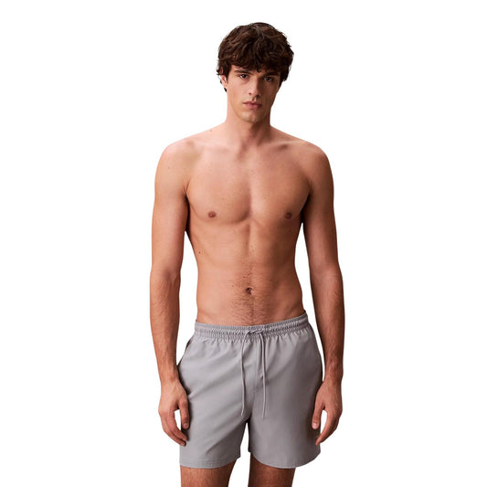 Boxer Mare CK Jeans Grigio; 100% Poliestere Impermeabile. Coulisse regolabile, tasche anteriori e posteriori con velcro, slip in rete. Lunghezza media, asciugatura ultra-rapida, stile moderno. Vista frontale 