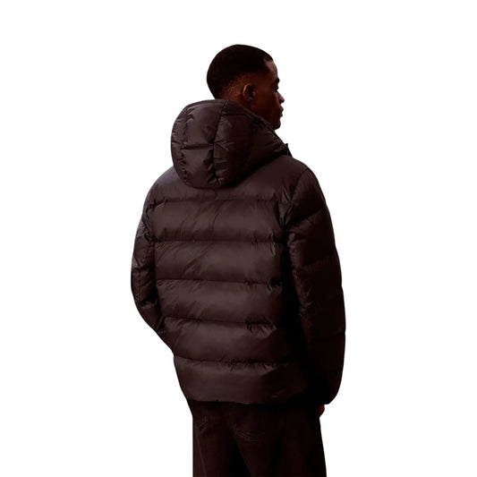 Piumino Calvin Klein uomo nero LV04RH502G. Giaccone invernale pesante bicolore style colour block in poliestere riciclato con cappuccio, logo CK, tasche laterali con cerniera e vestibilità regolare normal fit.