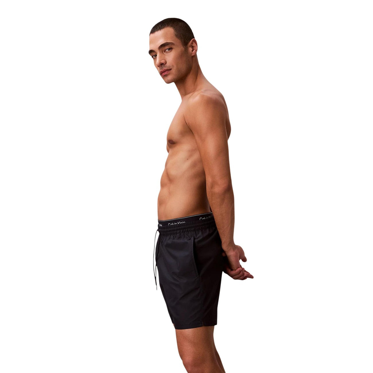 Boxer Mare CK Essentials; Tessuto Impermeabile. Doppia vita elastica logata, asciugatura rapida, lunghezza media. Tasca con velcro, slip a rete interno. Stile minimalista e funzionale per l'estate. Laterale 