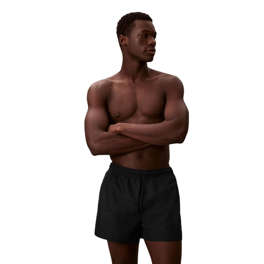 Calvin Klein Monogram Swim Shorts; neri, lunghezza corta, poliestere impermeabile, coulisse regolabile, logo iconico. Il costume essenziale per l'estate. Vista frontale 