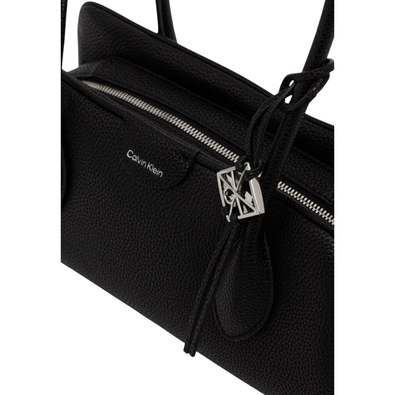 Borsa a Spalla Donna Calvin Klein Emblem Trio; Nero. 100% Poliuretano effetto martellato, chiusura superiore con zip, doppi manici e charm logo lucido. Silhouette compatta e allungata (30x15 cm), stile minimal contemporaneo. Dettaglio 