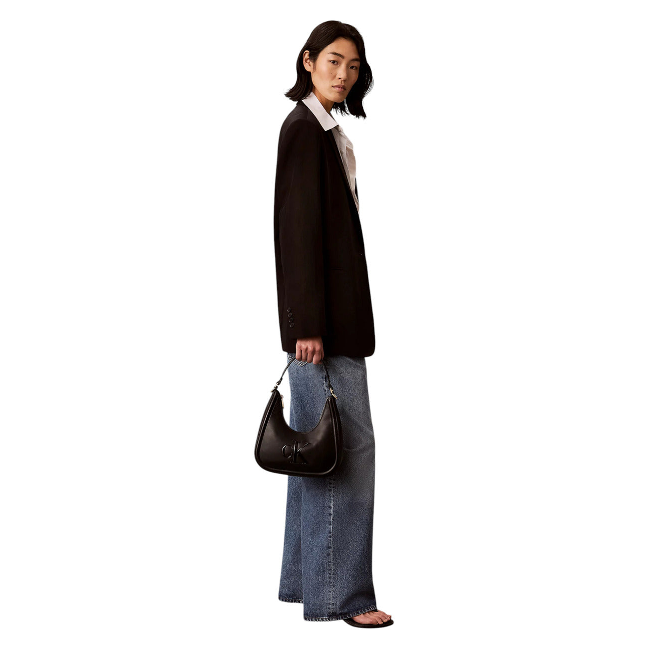 Borsa Mezzaluna Piccola Calvin Klein Bold; Nero. 100% Ecopelle poliuretano, manici corti e tracolla removibile, chiusura con zip. Dimensioni compatte (25x25,8 cm), stile minimalista e femminile 4 stagioni. Indossata da modella 