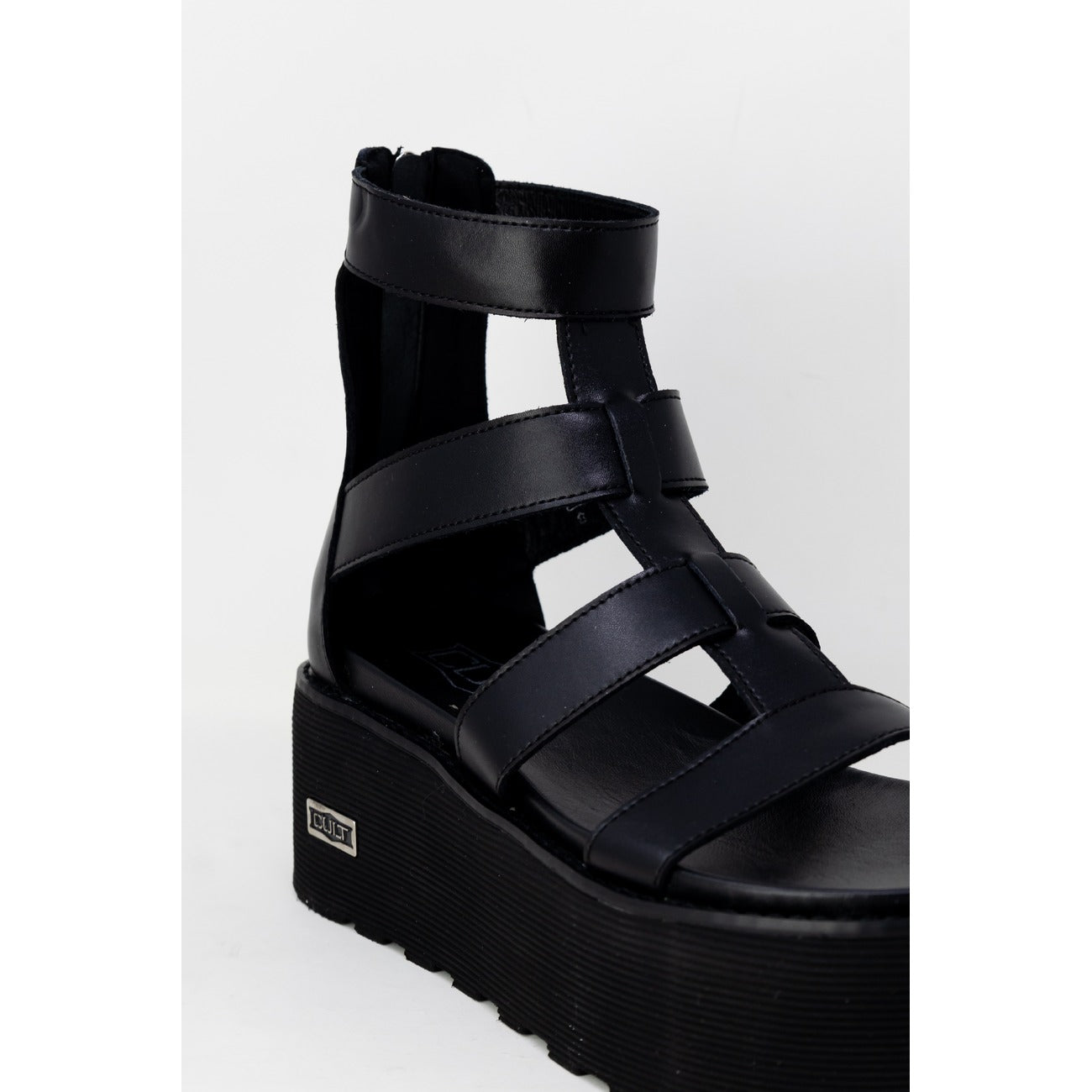 Sandali Platform Cult Nancy; Nero. Pelle e poliuretano, tacco 6 cm, suola dentellata. Chiusura con zip posteriore, logo metallico laterale. Stile grintoso e moderno. Frontale laterale 