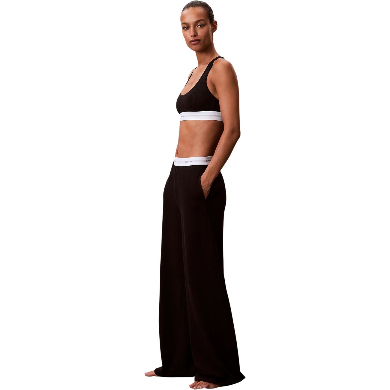 Pantaloni pigiama Calvin Klein donna neri modello LOGO JERSEY PANT. Pantalone lungo da notte e loungewear in maglia di cotone a coste tinta unita con tasche laterali e fondo con risvolto, dotato di fascia elastica logata in vita, stile casual sportivo e minimale.