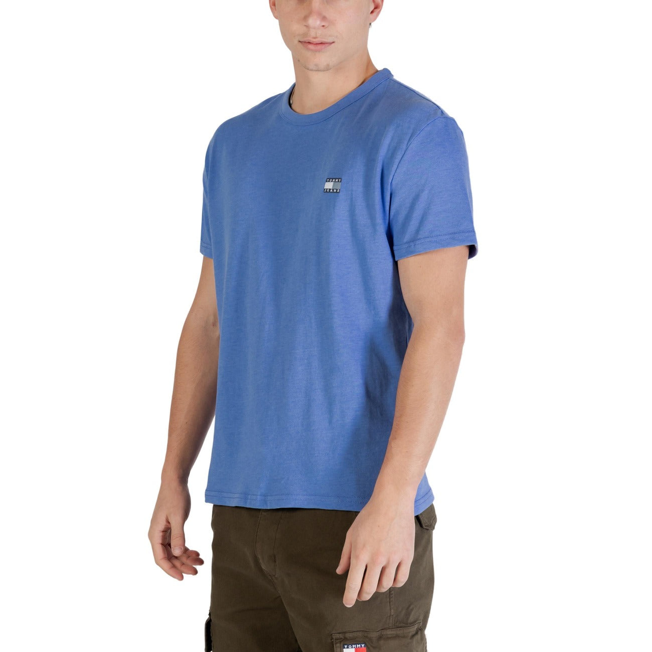 T-shirt Tommy Jeans Blu; 60% Cotone Rigenerato, 40% Poliestere Riciclato. Logo ricamato, maniche corte, vestibilità regular. Capo sostenibile ideale per tutte le stagioni, stile casual iconico. Frontale laterale 
