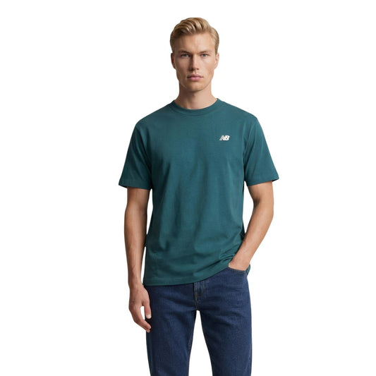 T-shirt New Balance Verde; 100% Cotone. Logo piccolo sul petto, maniche corte, girocollo. Vestibilità regular, perfetta per outfit casual e sportivi in ogni stagione. Vista frontale 