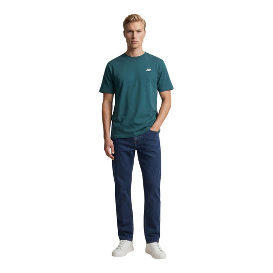 T-shirt New Balance Verde; 100% Cotone. Logo piccolo sul petto, maniche corte, girocollo. Vestibilità regular, perfetta per outfit casual e sportivi in ogni stagione. Figura intera 