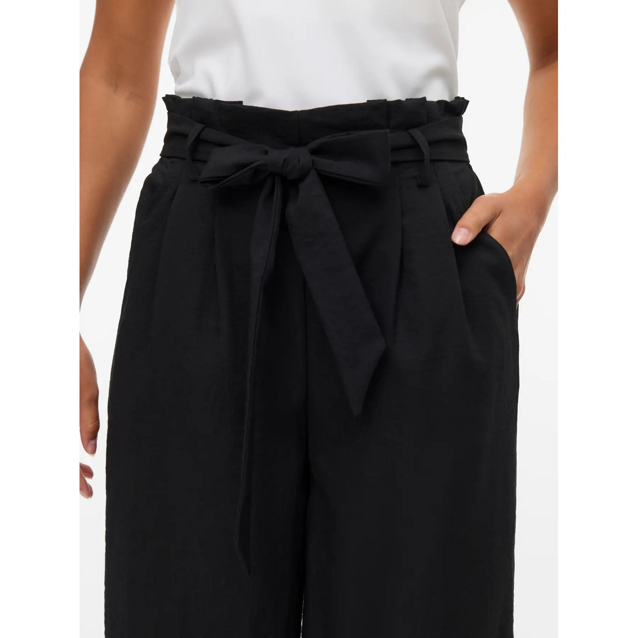 Pantaloni Donna Fantasia Nero Vero Moda Culotte; Taglio wide leg a gamba larga con lunghezza al polpaccio in misto viscosa fluida. Vita alta con cordino regolabile e tasche anteriori, stile casual primavera-estate. Vista Dettaglio fiocco 