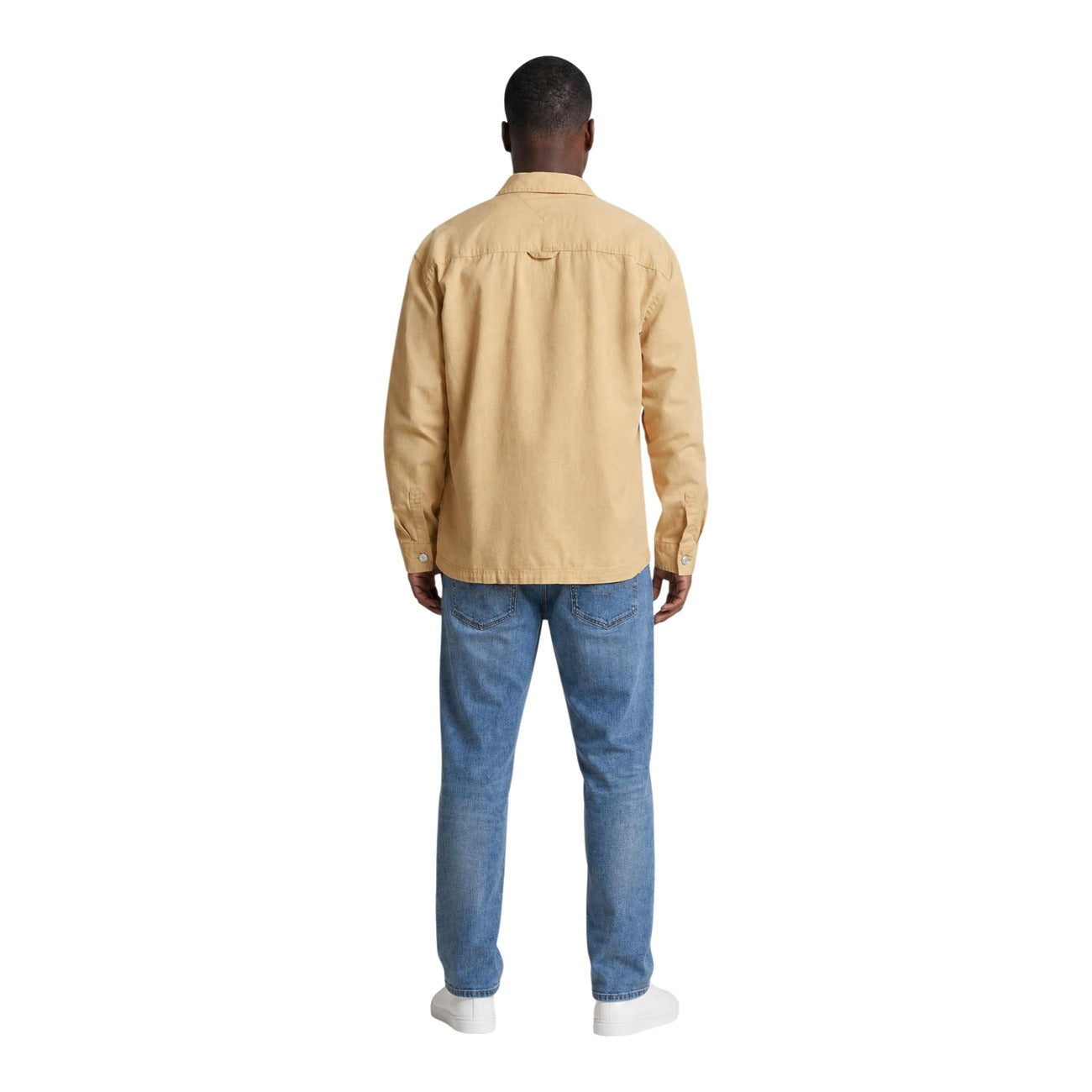 Camicia Beige Tommy Jeans; Utility Style. 100% Cotone Rigenerato. Doppia tasca frontale, logo ricamato, vestibilità regolare. Robusta, versatile e attenta all'ambiente. Vista posteriore figura intera 
