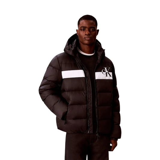 Piumino Calvin Klein uomo nero LV04RH502G. Giaccone invernale pesante bicolore style colour block in poliestere riciclato con cappuccio, logo CK, tasche laterali con cerniera e vestibilità regolare normal fit.