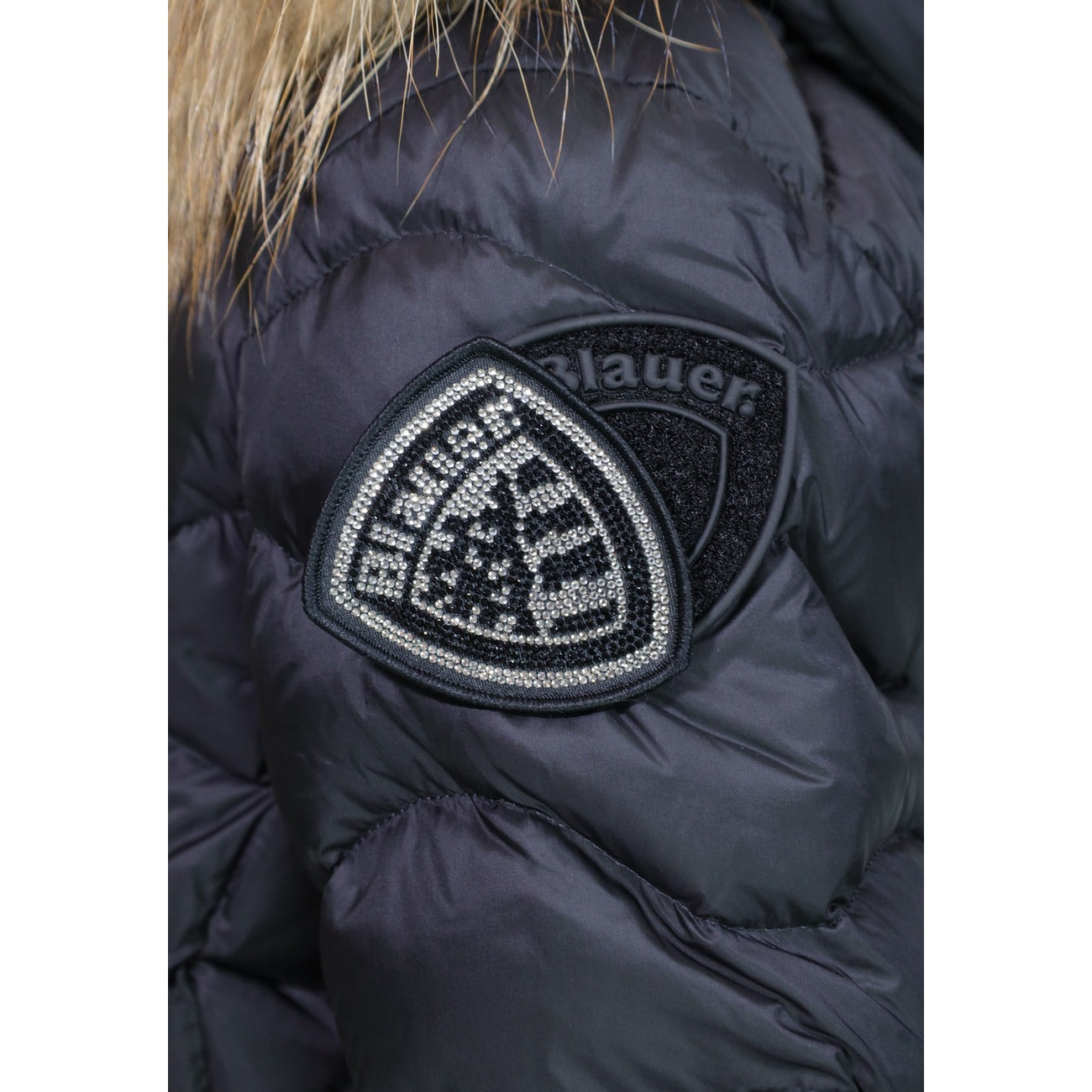 Piumino donna Blauer nero ecopelliccia Aldie 26WBLDC03034. Giubbotto corto da donna nero slim fit trapuntato a onde con cappuccio in pelliccia sintetica, zip doppio cursore e logo Blauer sulla manica, giacca invernale calda casual chic.