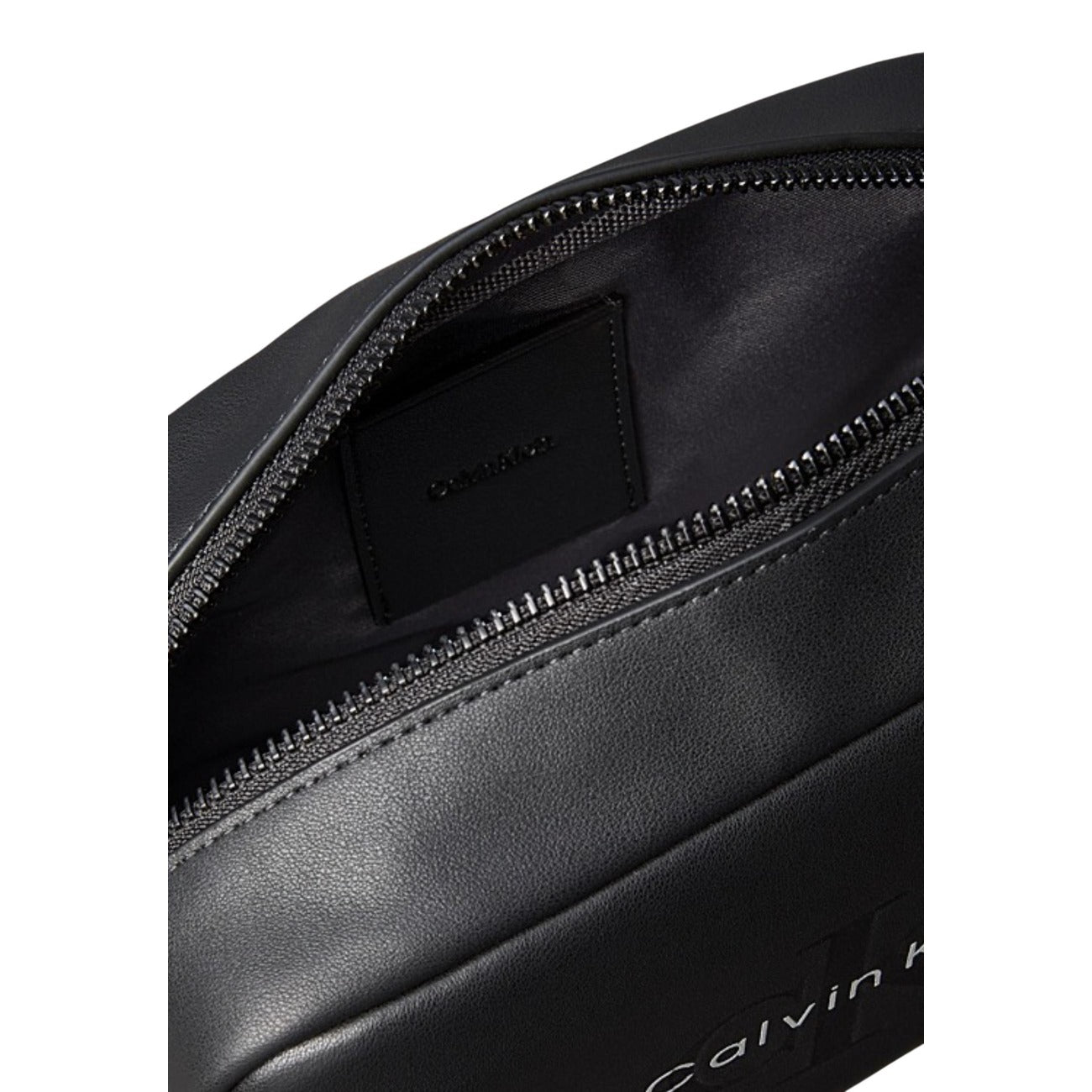 Calvin Klein Washbag; ecopelle nera, chiusura a zip, manico laterale. L'astuccio da bagno compatto e moderno per lo stile di vita contemporaneo. Colore nero. Vista frontale apertura cerniera 