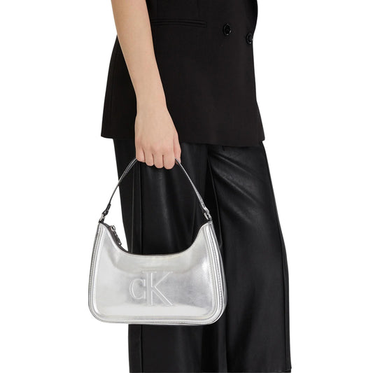 Borsa a spalla Calvin Klein Bold CK; Colore Argento Metallico. 100% Poliuretano, chiusura a zip, interno foderato con porta carte. Design capiente e futuristico. Indossata da modella 