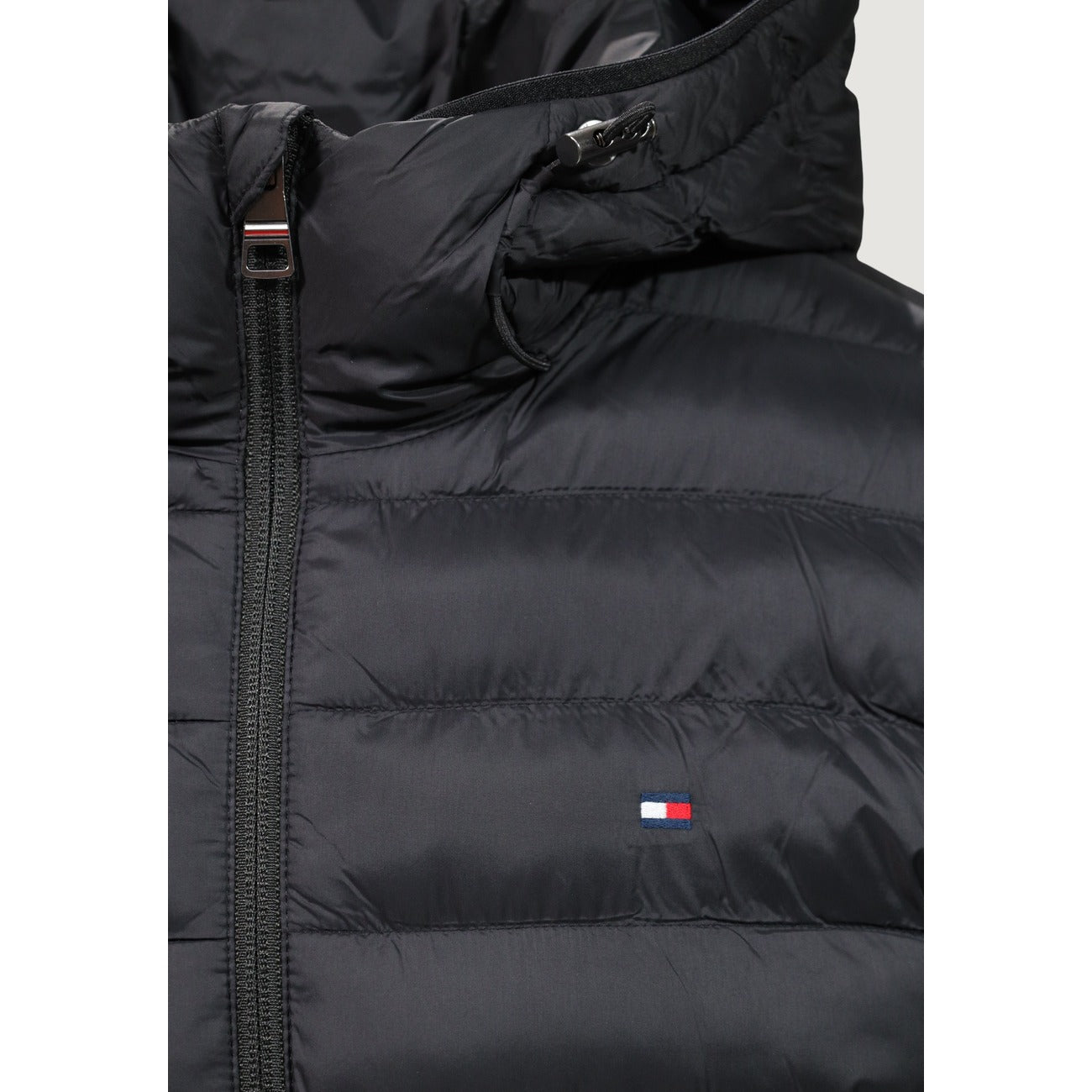 Piumino Tommy Hilfiger uomo nero MW0MW43464. Giacca imbottita trapuntata con cappuccio, 100% poliestere leggero e termico, vestibilità regolare, cerniera zip e tasche laterali con zip.