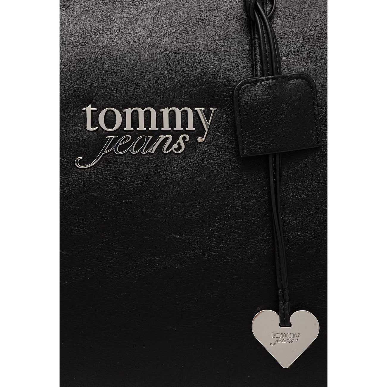 Borsa Shopper Grande Tommy Hilfiger TJW; Nero. 100% Poliuretano effetto pelle, chiusura con zip superiore, doppi manici a spalla, logo ricamato e charm a cuore metallico. Misure maxi e profonde (33,5x30x20 cm). Dettaglio logo 