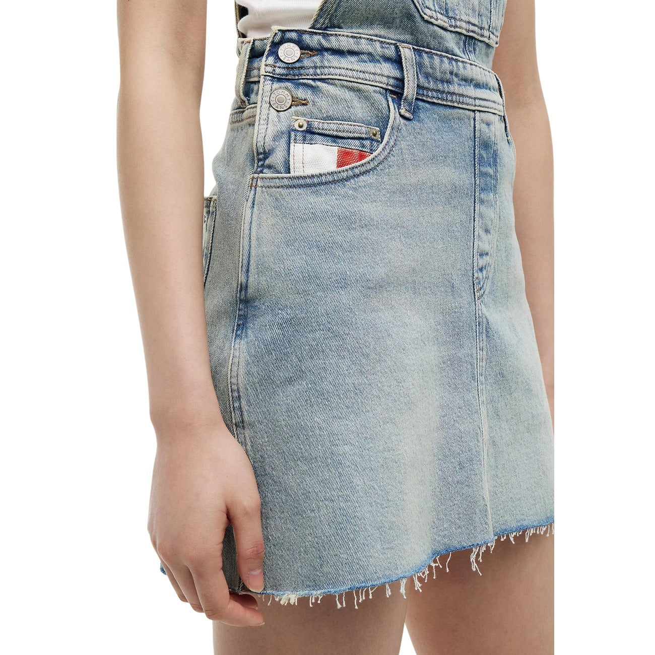 Abito salopette jeans Tommy Jeans donna modello DW0DW228741AB. Vestito corto in denim chiaro regular fit a cinque tasche con bretelle e bottoni metallici, tasca sul petto con mini bandiera logo Tommy, stile casual e streetwear in cotone biologico.