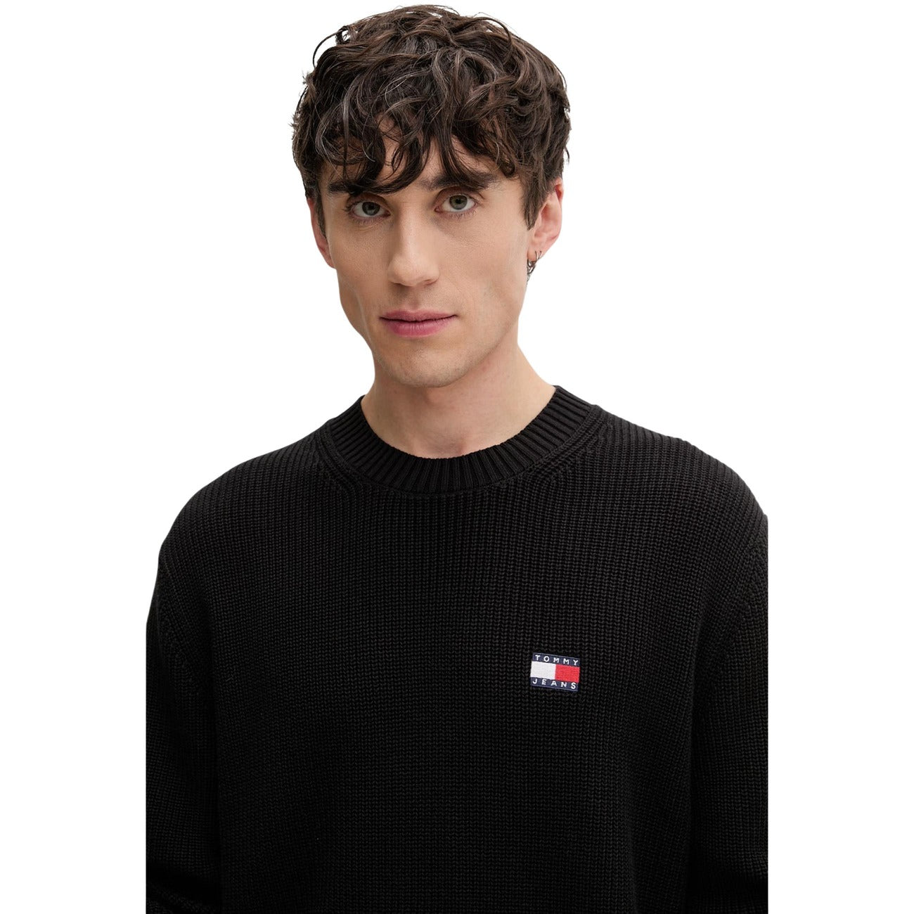 Maglione Tommy Jeans uomo nero DM0DM20923. Pullover a girocollo in cotone sostenibile con lavorazione a maglia spessa, maniche lunghe, bordi a costine e logo classico applicato sul petto.