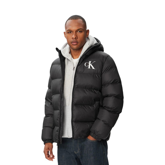 Piumino Calvin Klein uomo nero LV04RG513G. Giambotto pesante invernale in ecopiuma e nylon riciclato con logo CK, cappuccio, tasche con cerniera e vestibilità regolare normal fit.