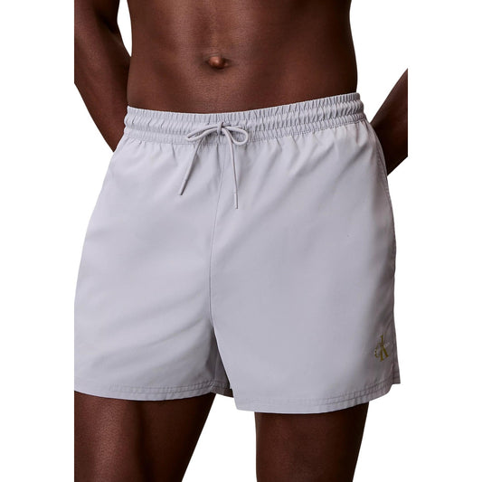 Costume Boxer Grigio Calvin Klein; 100% Poliestere Riciclato. Asciugatura rapida, vita con coulisse, logo sulla gamba. Stile mare minimale ed ecosostenibile.