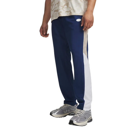 Pantaloni Under Armour uomo blu modello UA RIVAL WOVEN CB PANTS. Pantaloni lunghi da tute sportive e allenamento in poliestere con bande a contrasto colour block, vita elastica e tasche con cerniera, pantalone casual athleisure per la mezza stagione.