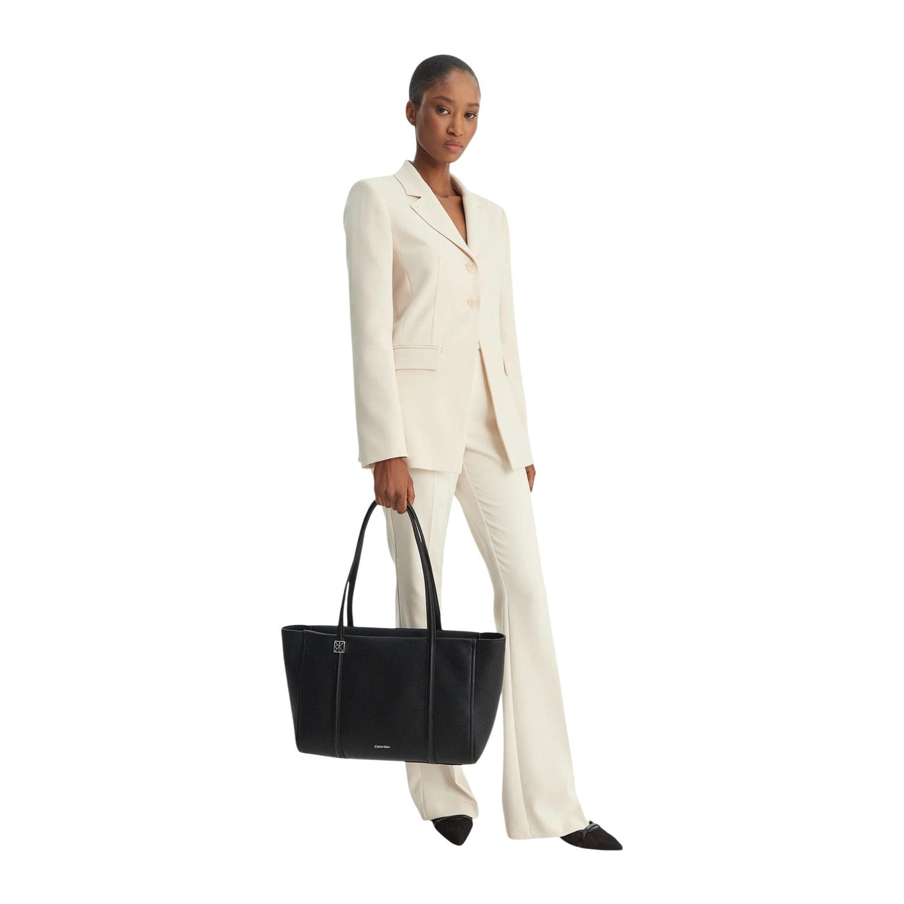 Borsa Tote Calvin Klein Emblem; 100% Poliuretano martellato. Chiusura con zip, doppi manici lunghi, dettagli dorati. Misure 48x25x15 cm. Borsa capiente 4 stagioni, stile casual-business. Indossata da modella 