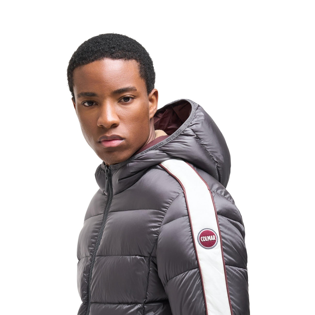 Piumino Colmar uomo grigio Heritage. Giaccone invernale bicolore idrorepellente con cappuccio, imbottitura in piuma d'oca naturale certificata RDS, tessuto riciclato e patch logo Colmar in feltro.