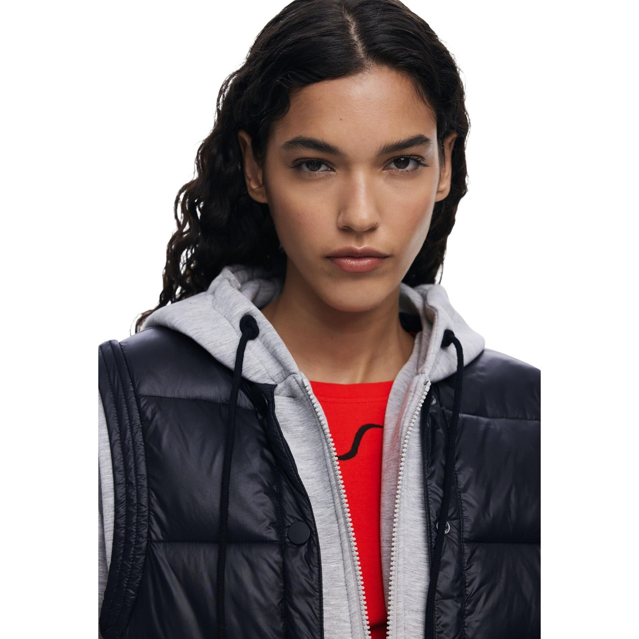 Felpa e Gilet 2-in-1 AW25; imbottitura termica, chiusura zip e bottoni, cappuccio regolabile. Il capo tecnico e stiloso disegnato a Barcellona.