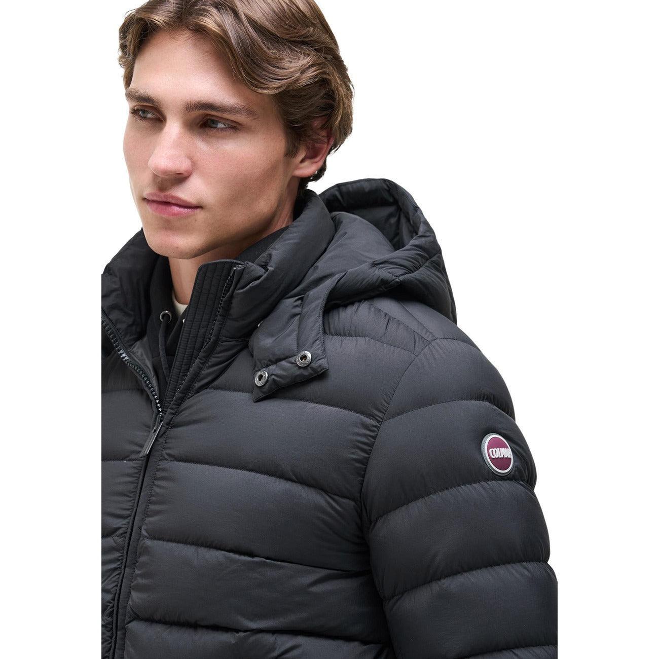 Piumino Colmar uomo nero opaco con cappuccio rimovibile. Giaccone invernale idrorepellente in piuma d'oca naturale certificata RDS, tessuto riciclato, coulisse sul fondo e patch logo Colmar Originals.