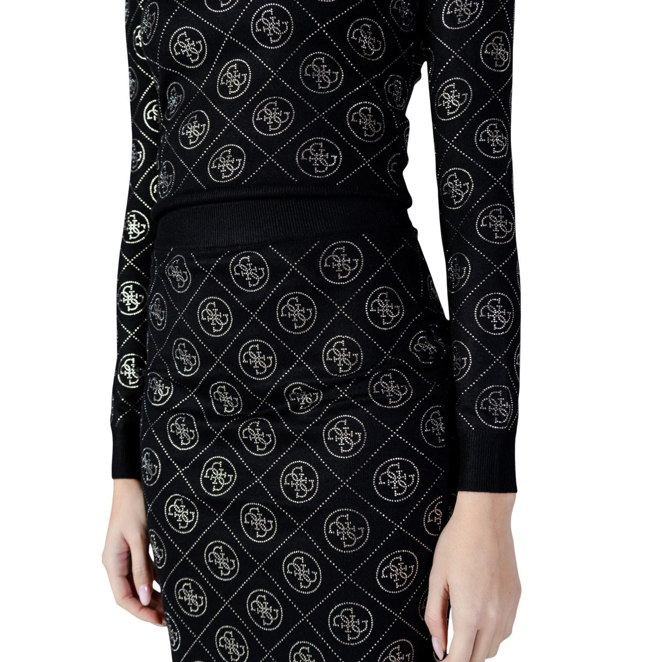 Guess Minigonna nera 4G Logo & Strass; gonna in maglia elasticizzata con rifiniture luminose e vita alta confortevole. Capo iconico e femminile dal carattere sofisticato. Vista frontale dettaglio logo 