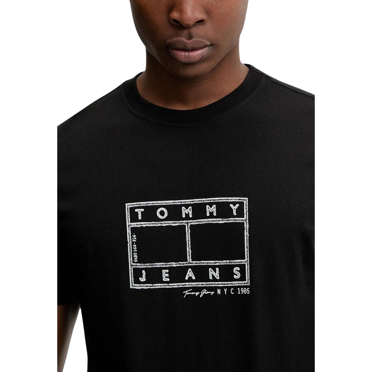 Tommy Hilfiger T-shirt nera Logo a Timbro; maglietta girocollo uomo in cotone morbido, stampa grafica circolare Tommy Jeans e dettagli iconici, perfetta per outfit quotidiani dinamici. Vista frontale dettaglio logo 