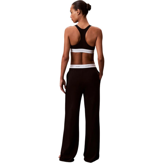 Pantaloni pigiama Calvin Klein donna neri modello LOGO JERSEY PANT. Pantalone lungo da notte e loungewear in maglia di cotone a coste tinta unita con tasche laterali e fondo con risvolto, dotato di fascia elastica logata in vita, stile casual sportivo e minimale.