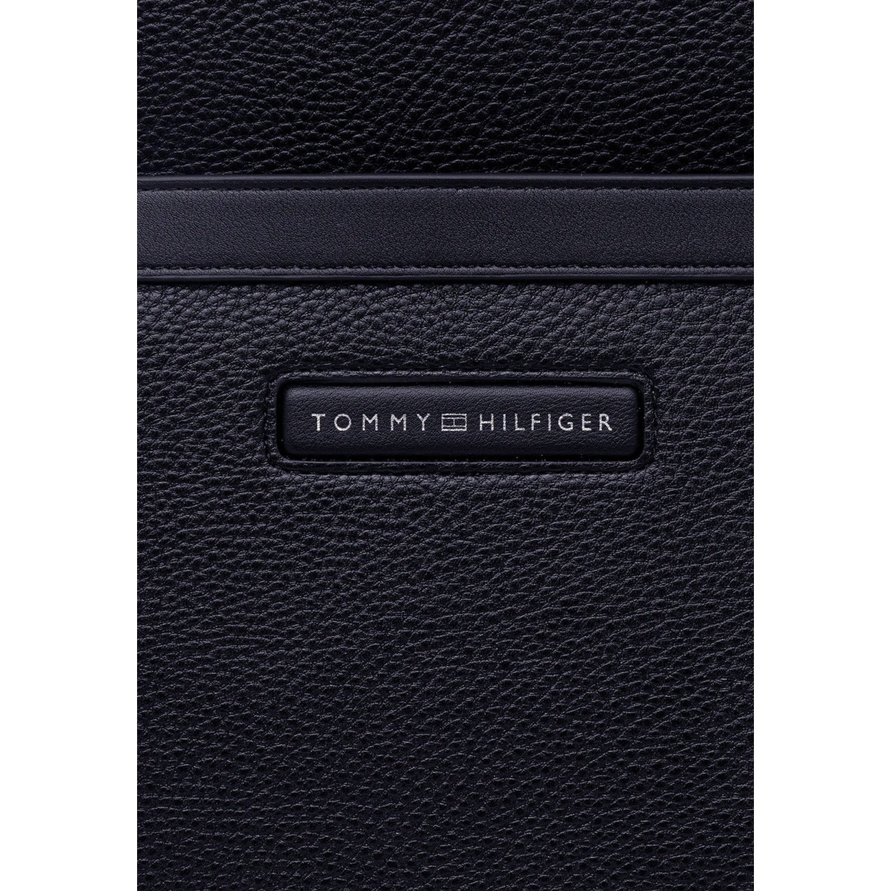 Zaino uomo Tommy Hilfiger; 85% Poliuretano, 15% Poliestere Riciclato Blu scuro. Spallacci imbottiti, tasca esterna, logo frontale. Zaino elegante e funzionale per lavoro e tempo libero. Vista frontale Dettaglio logo 